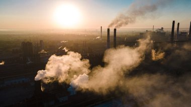 Fabrika dumanı bacalardan yükseğe doğru yükseliyor.