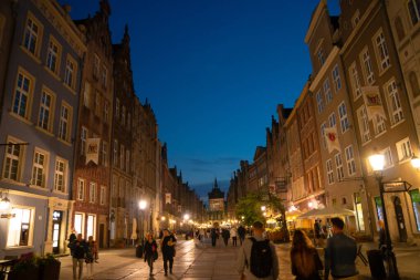 Scenic summer evening panorama of architectural pedestrians tourists people walk along the evening street of the Old Town GDANSK, POLAND - July 6, 2022