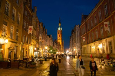 Scenic summer evening panorama of architectural pedestrians tourists people walk along the evening street of the Old Town GDANSK, POLAND - July 6, 2022