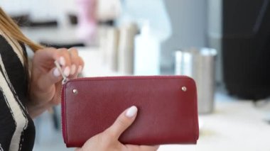 Hands of a young girl open a burgundy wallet