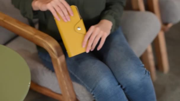 Een jong meisje legt een grijze tas op tafel — Stockvideo