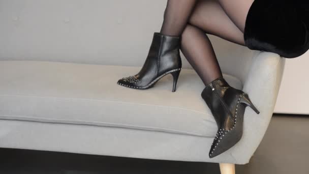 Bir kız kanepeye oturur ve siyah ayakkabılarını gösterir. — Stok video