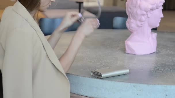 Una joven se sienta en una mesa con un bolso — Vídeo de stock