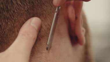 Berber dükkanında saç kesimi yapan genç adam. 