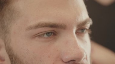 Berber dükkanında saç kesimi yapan genç adam. 