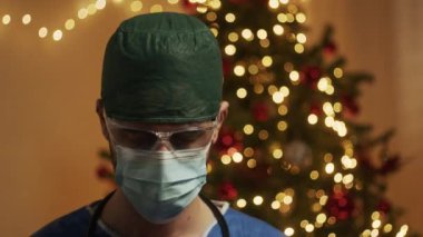 Noel arkaplanındaki maskeli genç erkek doktor. 