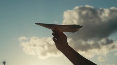 Erkek eliyle gökyüzüne karşı kağıt uçağın kesilmiş görüntüleri.