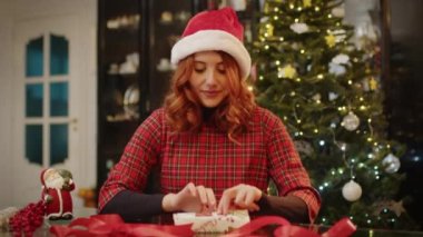 Evde genç bir kadının Noel hediyesi paketlediği video. 