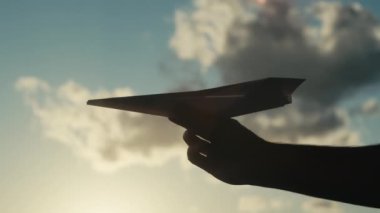 Erkek eliyle gökyüzüne karşı kağıt uçağın kesilmiş görüntüleri.