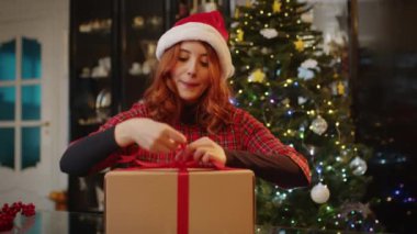 Evde genç bir kadının Noel hediyesi paketlediği video. 