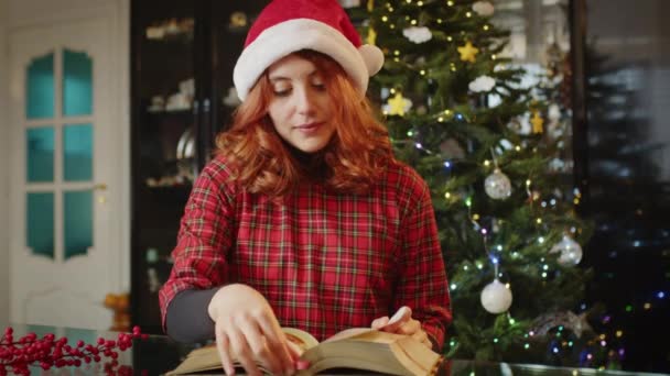 Jonge Vrouw Lezen Boek Met Kerst Decoraties Achter Video — Stockvideo