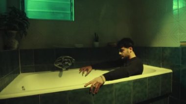 Young depressed boy goes into the bathtub