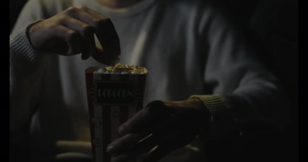 Мальчик ест попкорн, сидящий в закрытом кинотеатре — стоковое видео