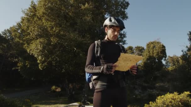 Chico ciclista mira el mapa de su ruta de montaña — Vídeos de Stock