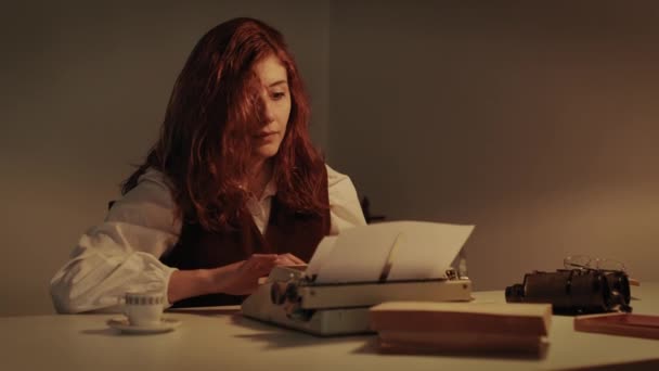 Młoda dziewczyna pisze na maszynie do pisania przy stole — Wideo stockowe
