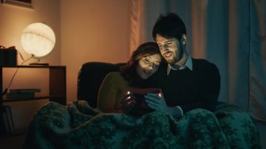 Bir çift erkek ve kız Sevgililer Günü ev partisi için bir hediye kutusu açıyor.