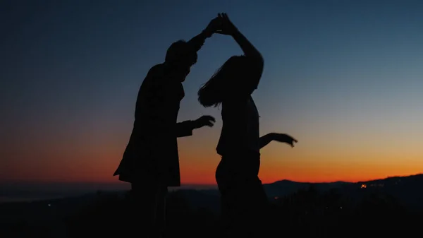 Siluet anak laki-laki dan perempuan riang menari saat matahari terbenam — Stok Foto