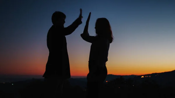 Silueta de niño y niña choca cinco al atardecer —  Fotos de Stock