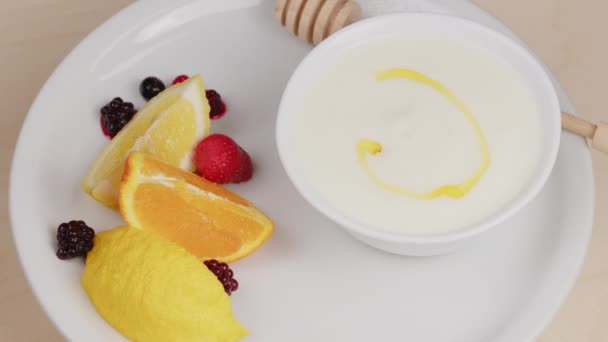 Мед падает в чашку с обычным йогуртом — стоковое видео