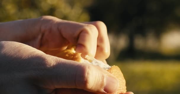 La mano está pelando una fruta naranja en el campo en la naturaleza. — Vídeo de stock