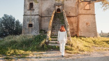 Beautiful girl in white dress enters an ancient castle in the countryside  clipart