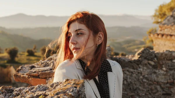 Gadis cantik dengan gaun putih menjelajahi sebuah kastil Italia kuno saat matahari terbenam — Stok Foto