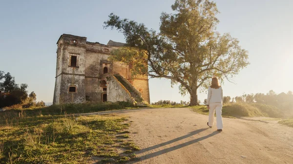 Vakre pike i hvit kjole går inn i et gammelt slott på landet. – stockfoto