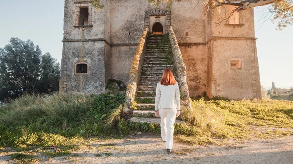 Gadis cantik bergaun putih memasuki sebuah kastil kuno di pedesaan — Stok Foto