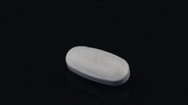 Siyah ayna yüzeyinde dönen beyaz hap.