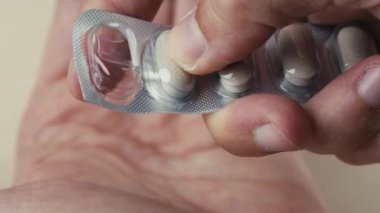 Evdeki kutudan hap kapsülü alan bir adamın eli.