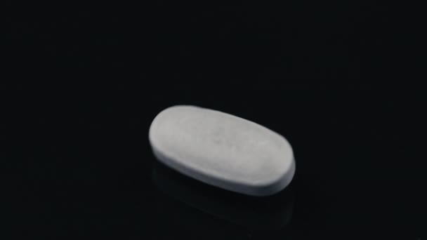 黑色镜面上旋转的白色药丸 — 图库视频影像