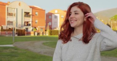 Genç ve güzel bir kız parkın içinde elleri açık bir kalp yapar.
