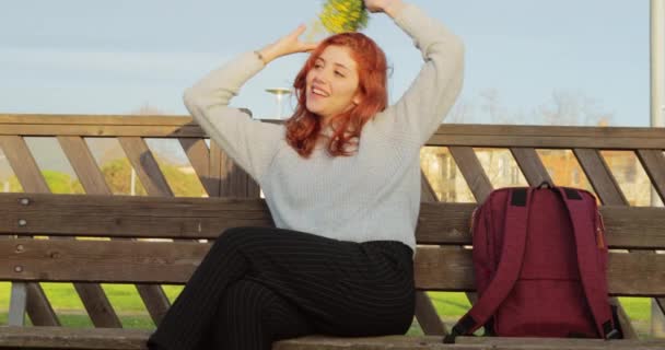 Ung flicka slappnar av sitter på bänken med en liten bukett mimosa — Stockvideo