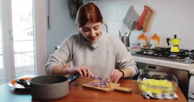 Kız mutfak masasında sotelenmek için soğan kesiyor.