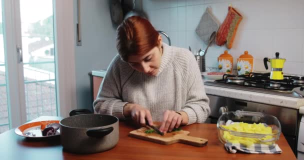 A lány hagymát vág a házi konyhaasztalon való sütéshez. — Stock videók