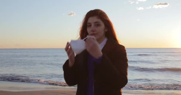 女の子オンザビーチで日の出の海置くオンザffp2マスク — ストック動画