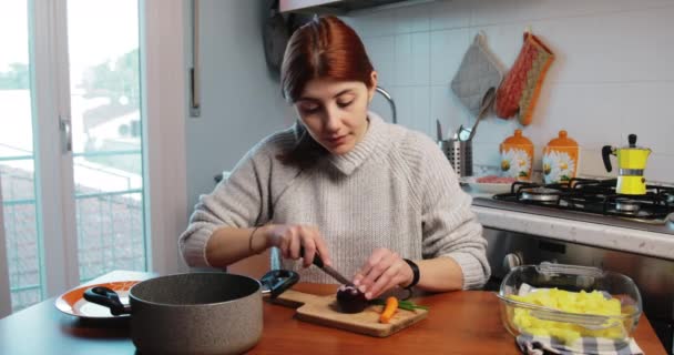 Κορίτσι κόβει κρεμμύδι για sauteeing στο τραπέζι της κουζίνας σπίτι — Αρχείο Βίντεο
