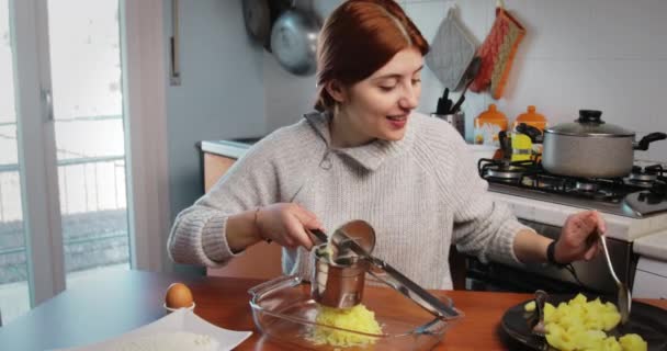 Menina está triturando batatas cozidas para a preparação de bolinhos e croquetes — Vídeo de Stock