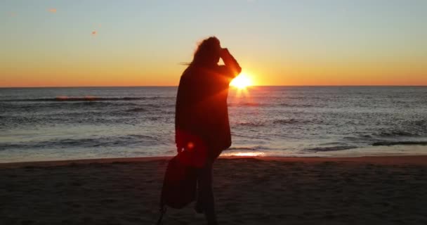 Silhuett av flicka har kul vid havet vid soluppgången på stranden på vintern — Stockvideo