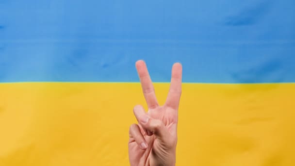 Mano nel simbolo della vittoria con bandiera ucraina per sfondo — Video Stock