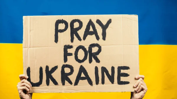 Cartón diciendo rezar por las víctimas en Ucrania con bandera amarilla y azul —  Fotos de Stock