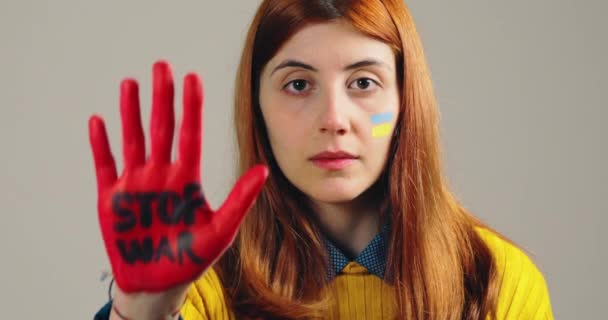 女の子はウクライナの恐怖を停止するためにストップ戦争で彼女の赤い手を上げる — ストック動画