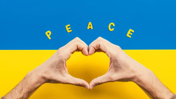 Symbol serca wykonane z rąk i ukraińskiej flagi na tle — Zdjęcie stockowe