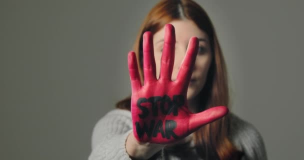 Молодая девушка бунтует против войны и говорит остановить с письменной красной рукой — стоковое видео