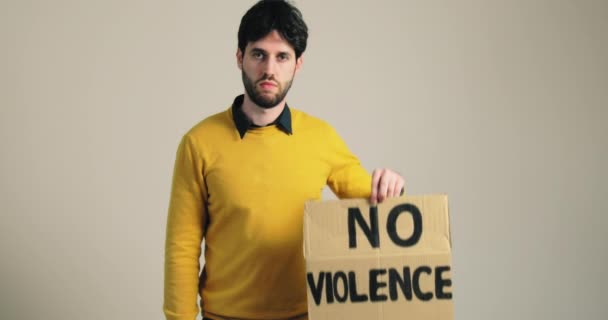 Un niño con una camisa amarilla levanta un cartel de protesta que dice que no hay violencia — Vídeos de Stock