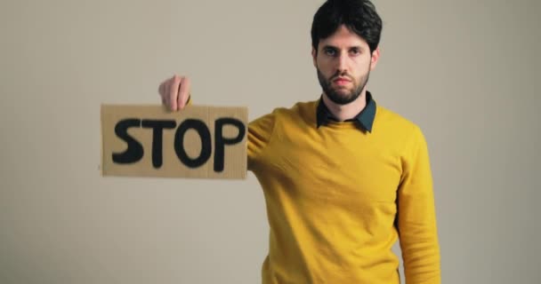 Chłopiec w żółtej koszuli trzyma zatrzymać billboard wojenny w ręku — Wideo stockowe