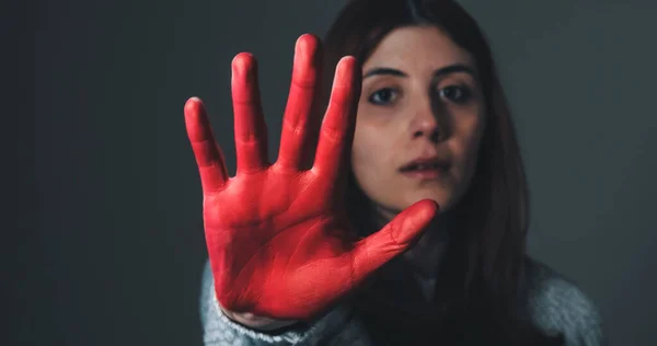 Smutná dívka zvedne ruku natřenou červeně zastavit a protestovat proti násilí — Stock fotografie