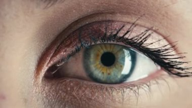 Güzel bir kızın mavi gözü yavaşça açılıyor.