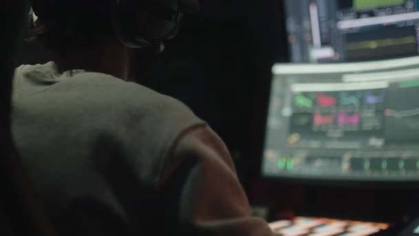 Sound engineer seen seated from behind uses the computer to mix audio music — Stock Video