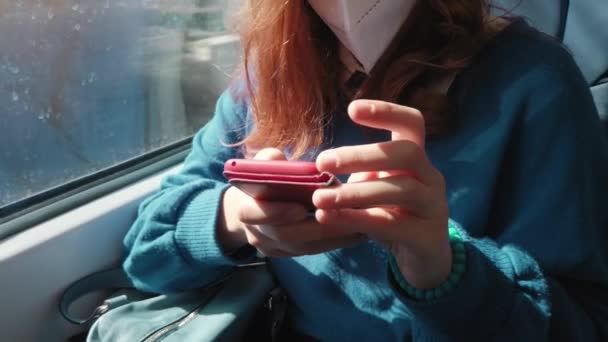 Молодая девушка путешествует на поезде со смартфоном и маской ffp2 — стоковое видео